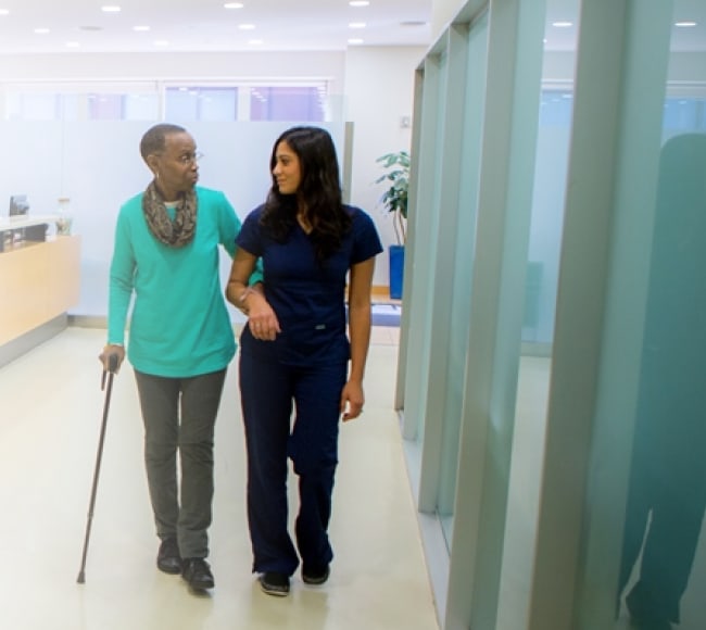 An IMSMP nurse walking alongside a patient in the clinic